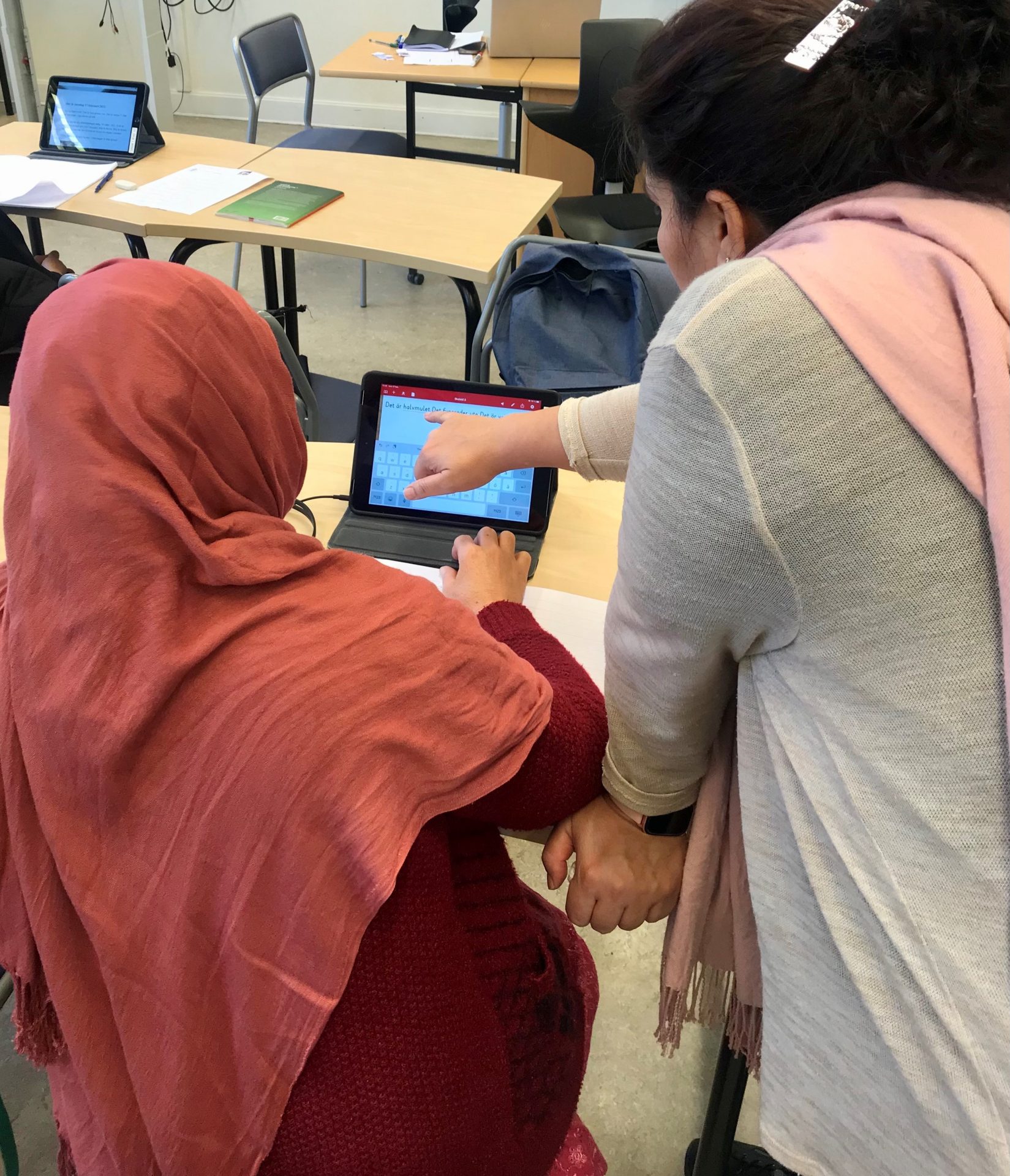 En språkstödjare hjälper en sfi-elev med iPad.
