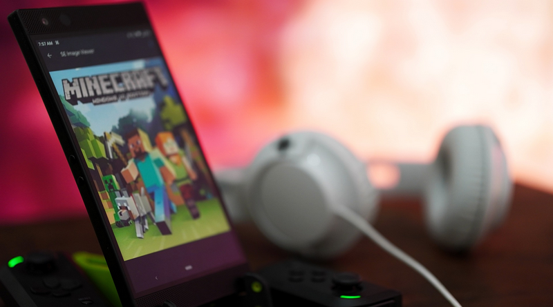 Telefon som visar spelet minecraft och ett par hörlurar