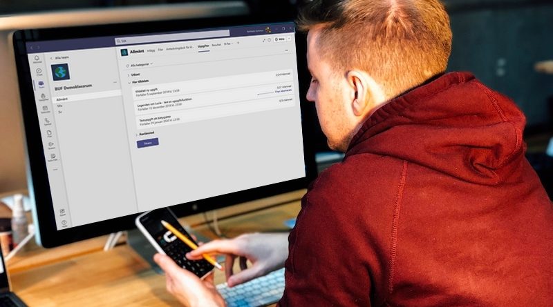 En kille kollar i mobilen och har samtidigt Teams på datorskärmen.